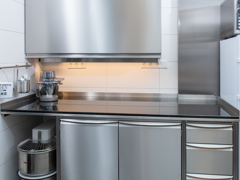 Wandhängeschrank mit Hebetür; darunter Niro-Verbau mit Hygienegriffleisten und Stein-/Granitabdeckung